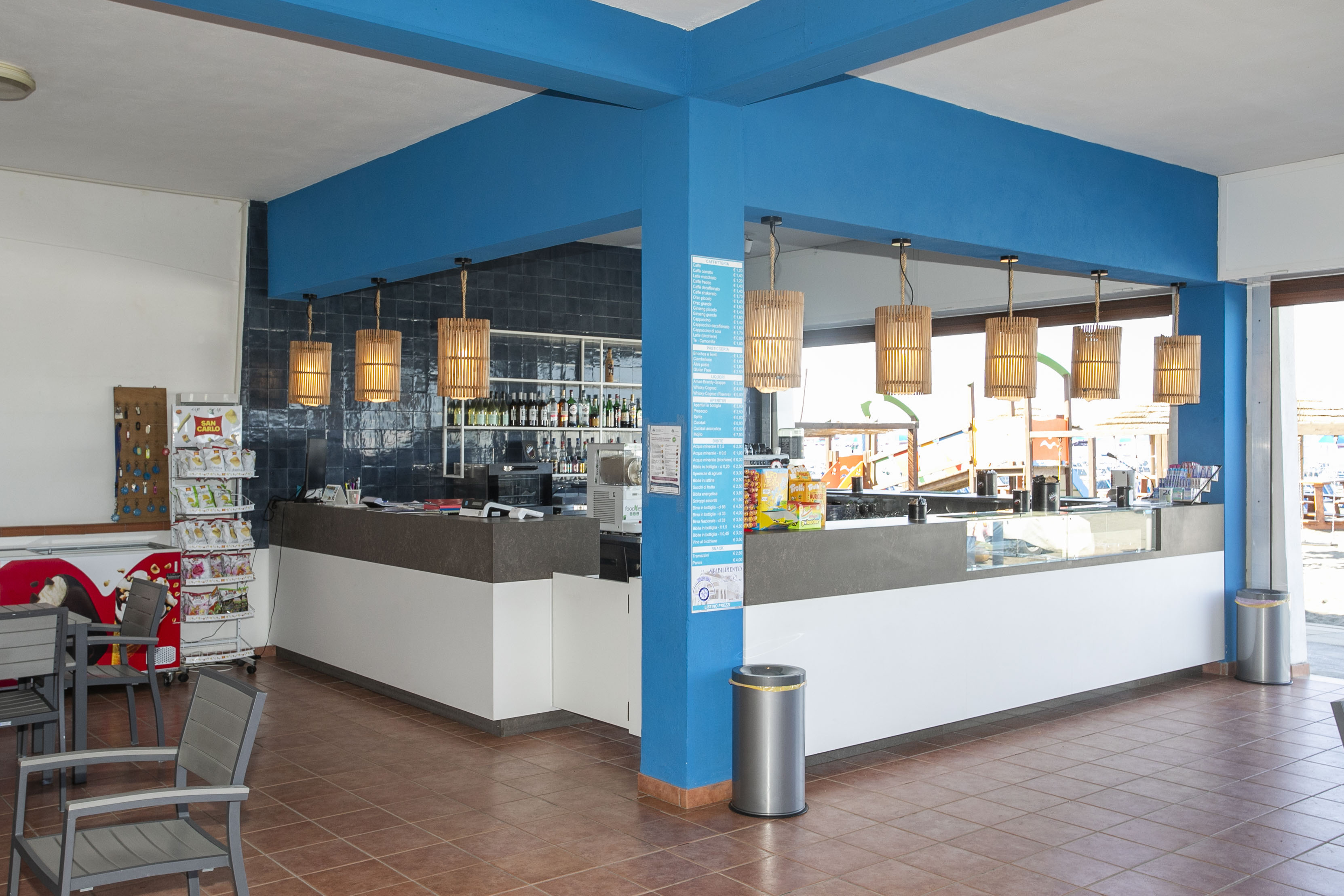 Modern hotel lobby with blue structures, white ceilings and tiled floors.