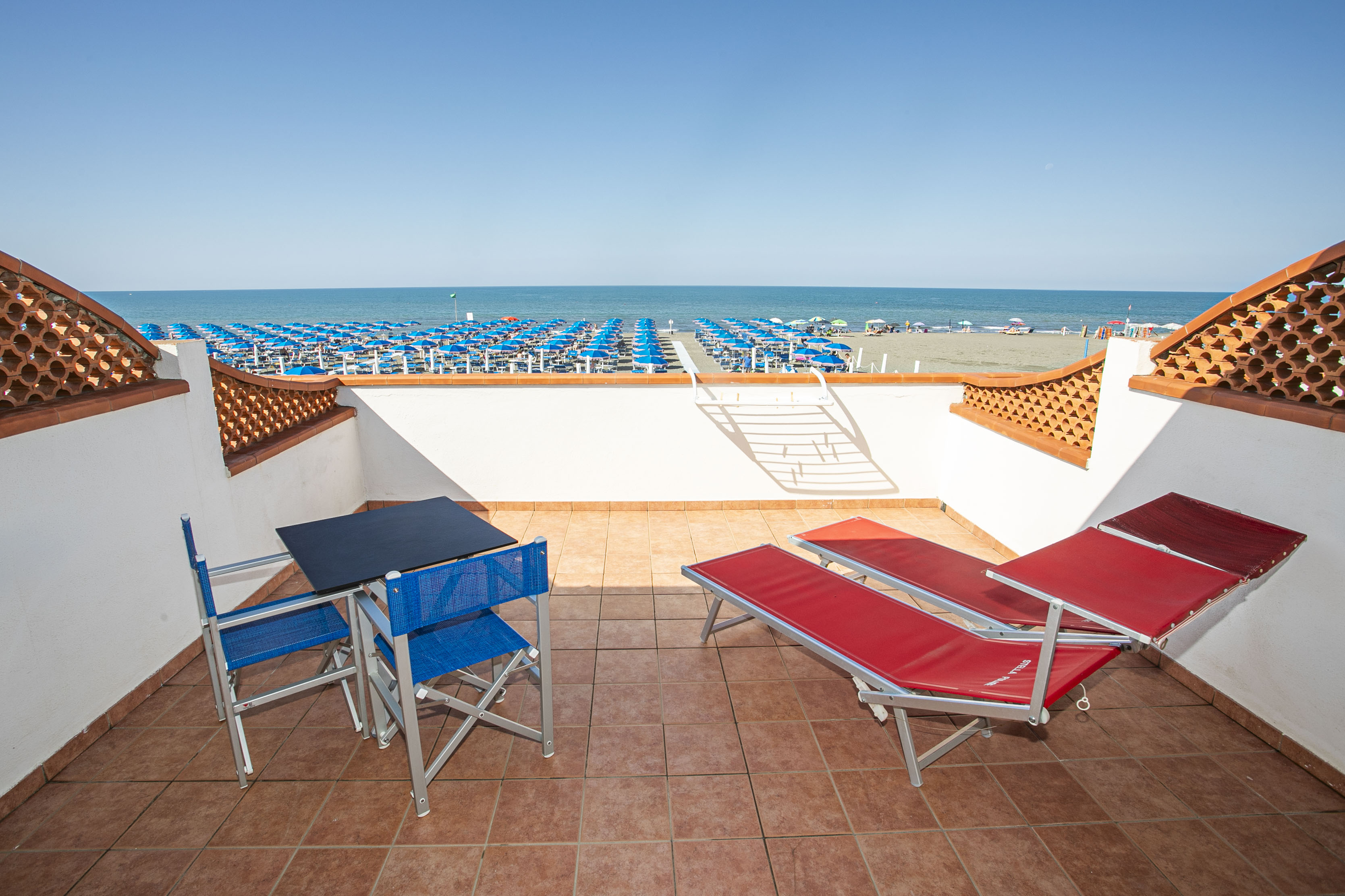 A beach scene with a patio. This photograph depicts a serene beach scene, featuring a patio equipped with two adjustable l...
