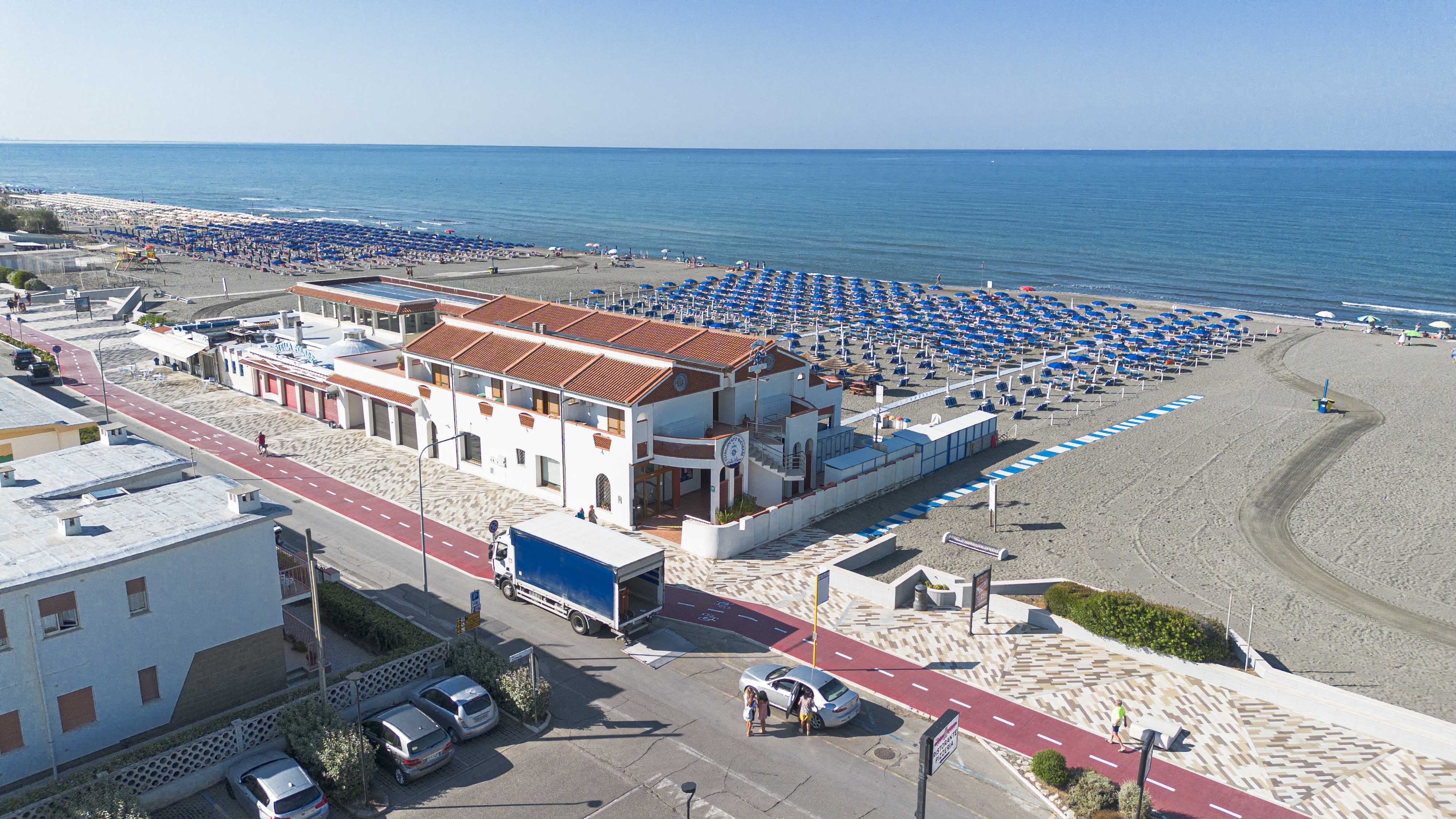Image description: Overhead view of a white building, including a white truck on a street with a red bike lane, in front o...